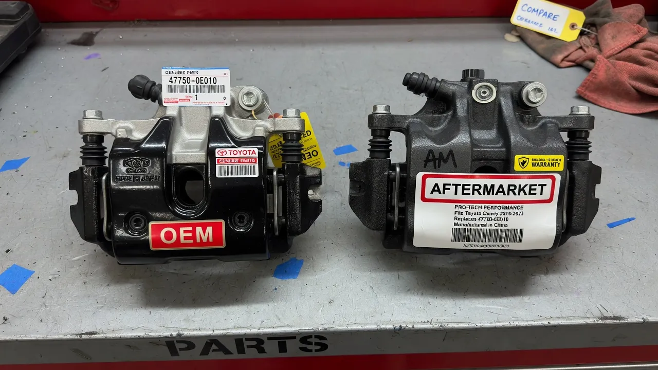 A close-up photo of two auto parts side by side on a workshop bench: one labeled 'OEM' with manufacturer branding, one labeled 'Aftermarket' with a ge...